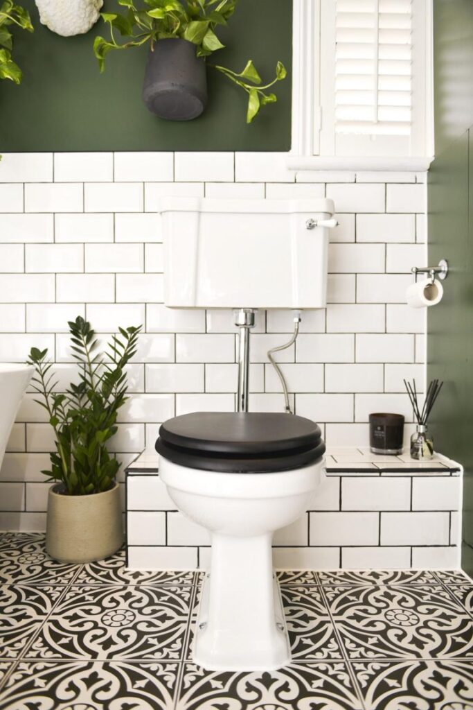 Bathroom with green walls, white subway tiles, and plants