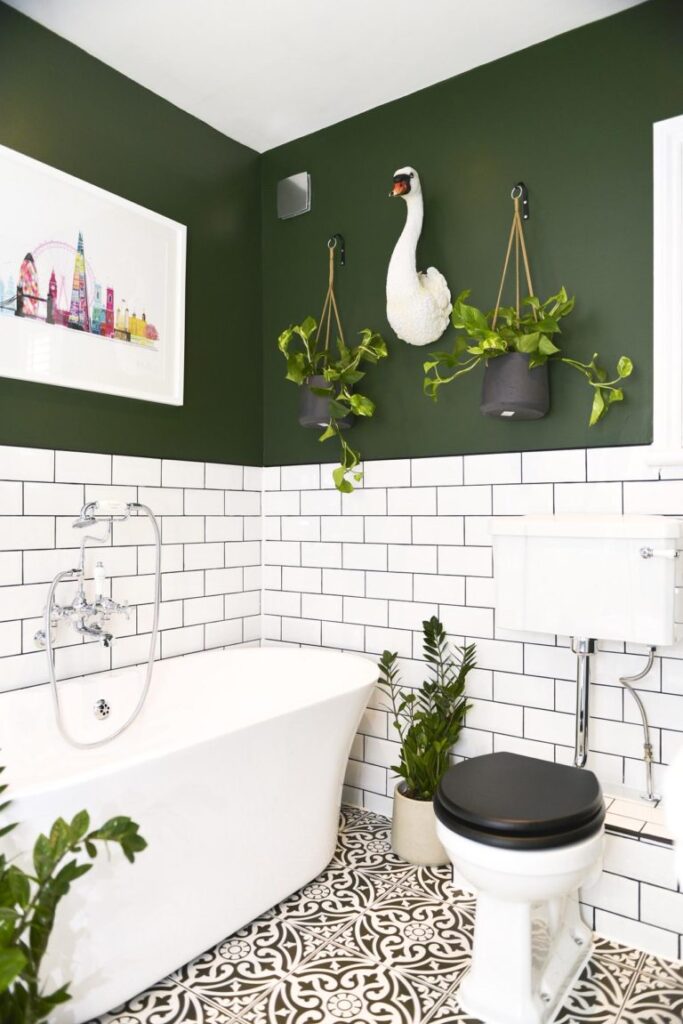 Bathroom with a white tub, green walls, and decorative plants