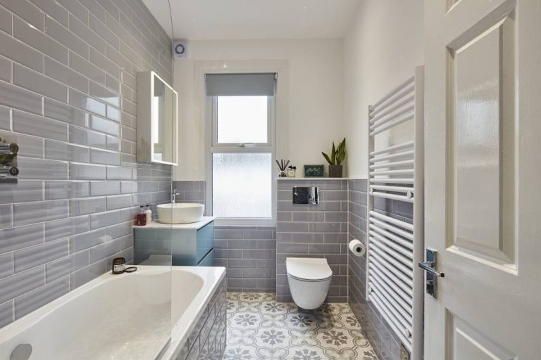 Bathroom with a bathtub, grey tiles, and patterned floor tiles