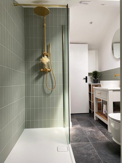 Shower room with gold fixtures and green tiles.