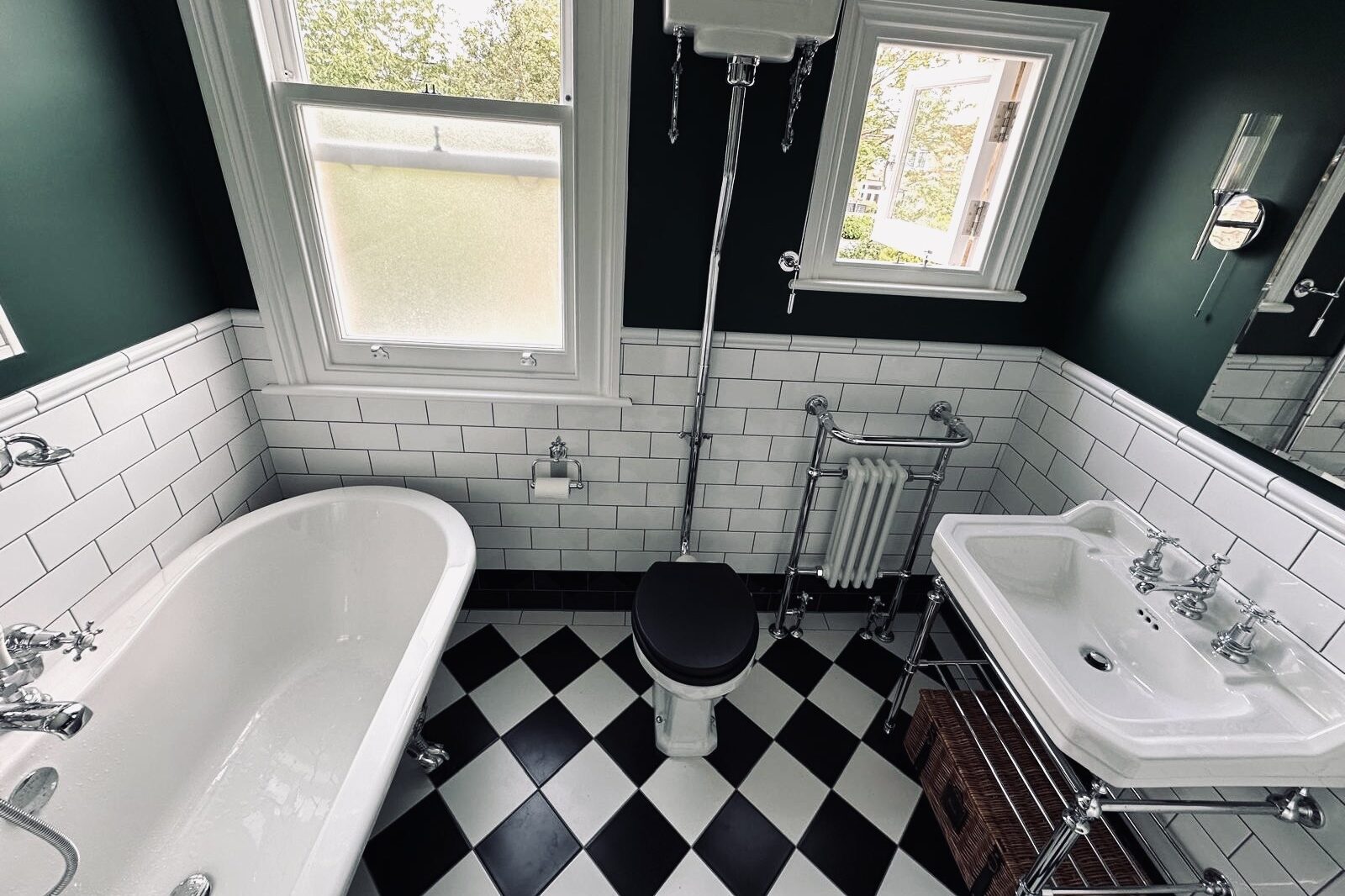 Vintage-style bathroom sink with chrome fixtures, black toilet seat, and checkered floor.