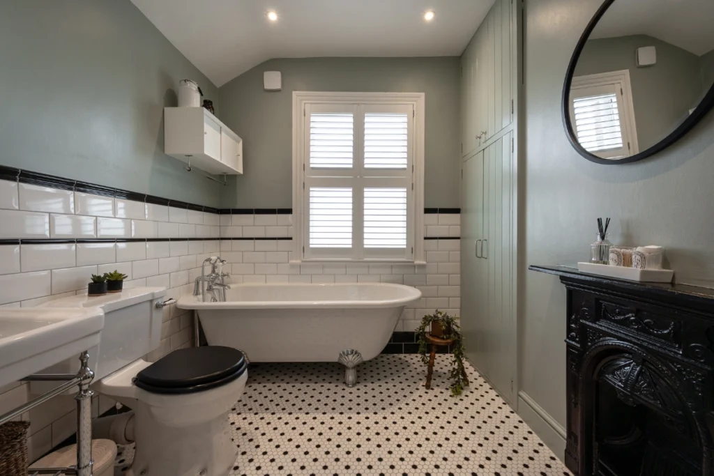 blackheath-victorian-bathroom-side-view Victorian bathroom overview with freestanding bath, green cabinetry and tiled walls.
