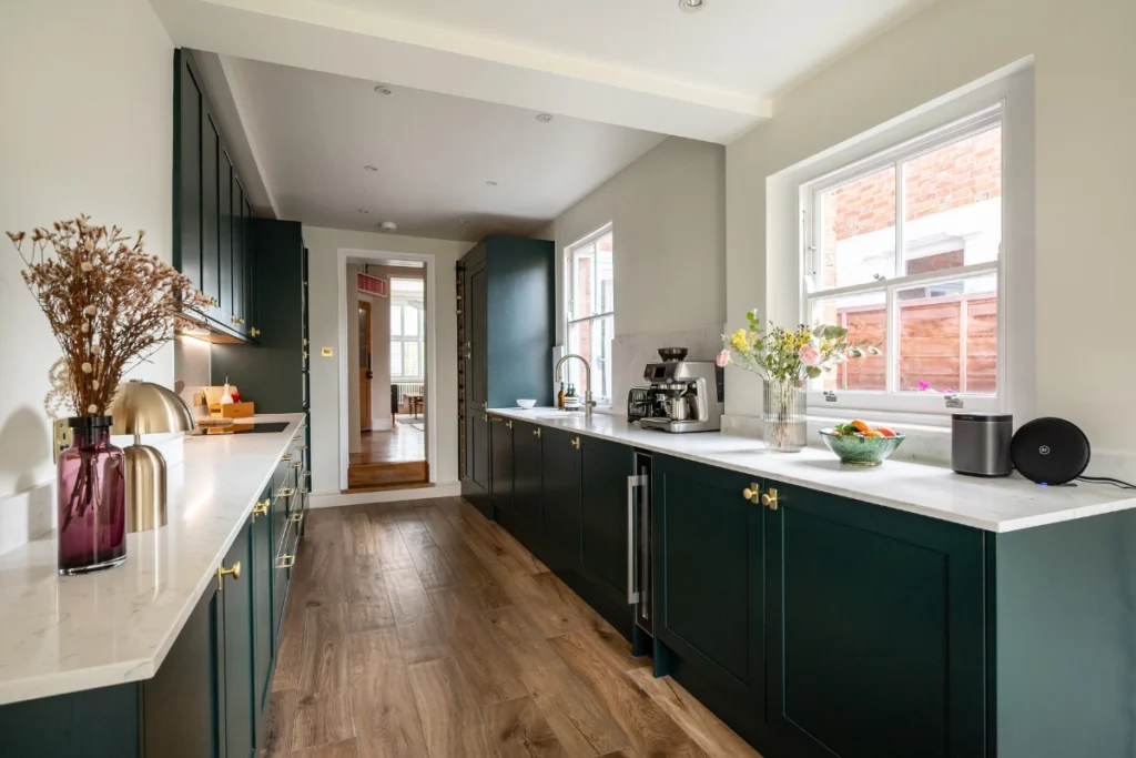 forest-green-shaker-kitchen-full-view Full view of dark green galley kitchen with quartz surfaces and brass handles.