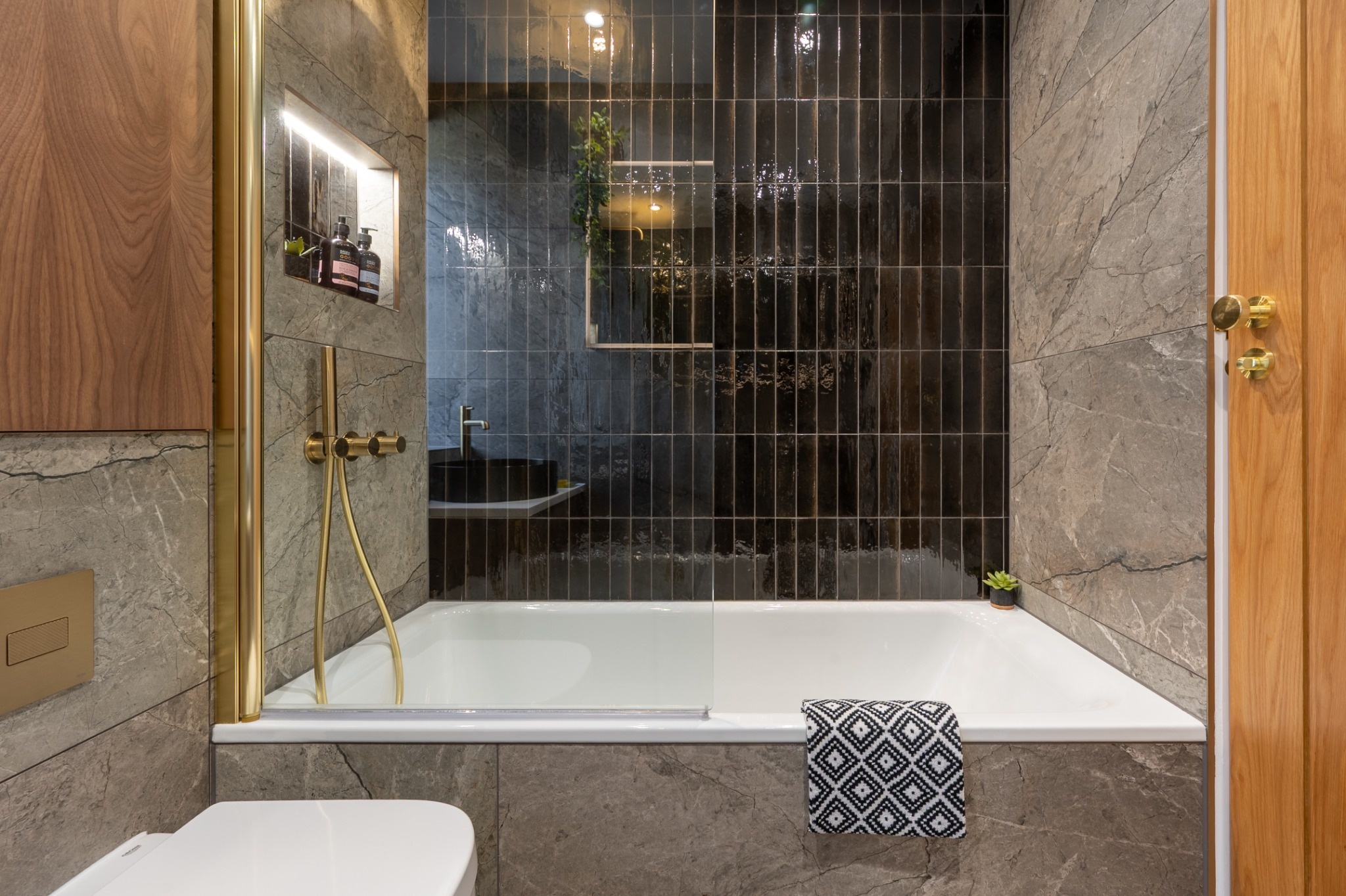 boutique-luxe-bathroom-black-gloss-tiles-brass-shower.jpg